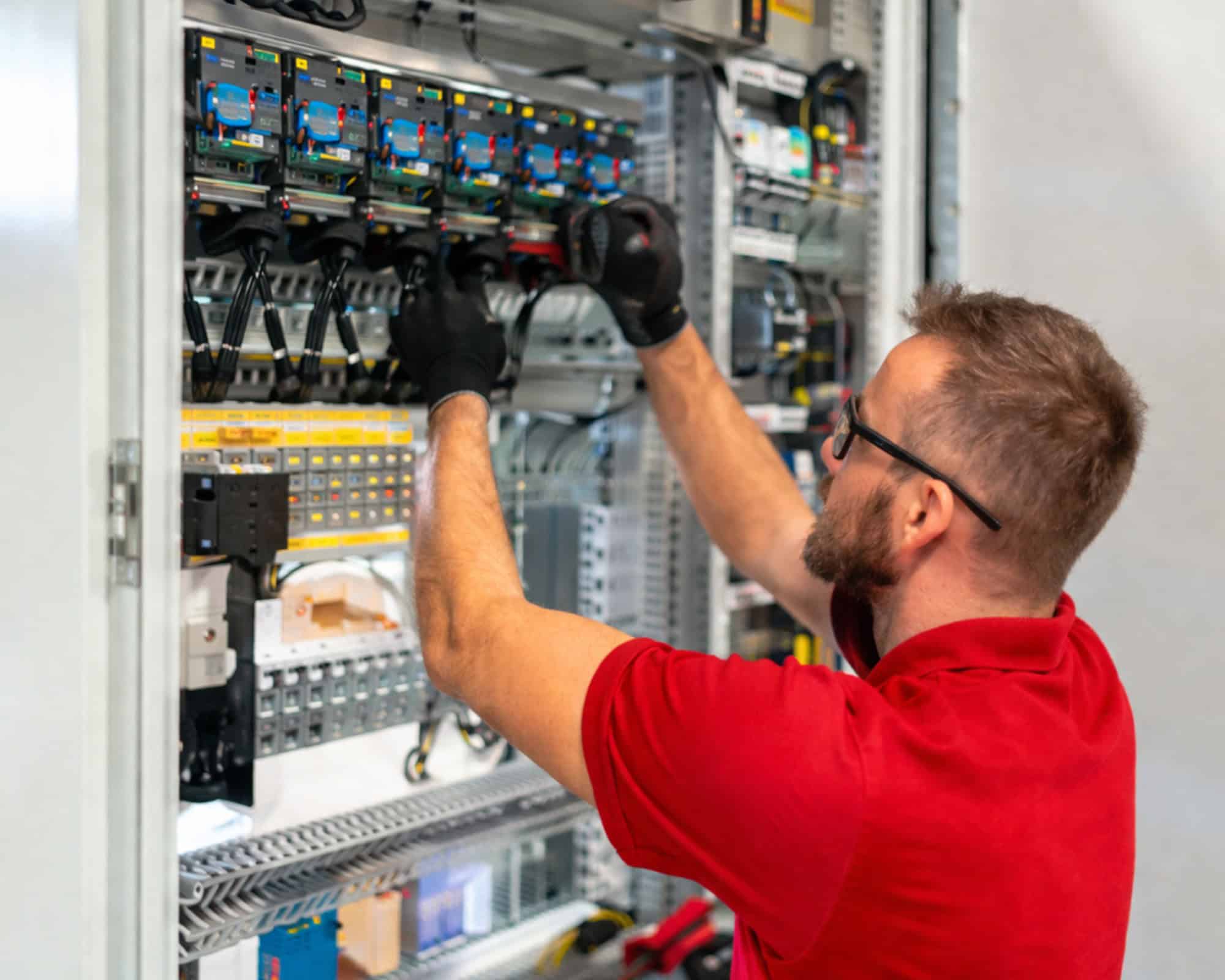 Elektriker installiert und wartet elektrische Komponenten im Schaltschrank.